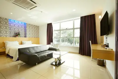 a bedroom with a bed and a couch and a desk at East Sun Hotel Sekinchan in Sekincan