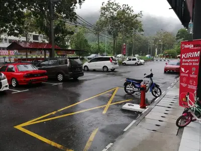 a parking lot with cars and a motorcycle parked on a street at WORLD KIDS FANTASY in Lumut