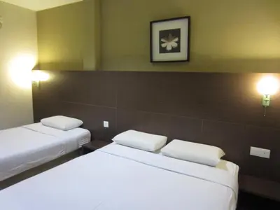 two beds in a hotel room with white pillows at Radiant Hotel in Sitiawan