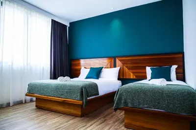 a bedroom with two beds and a blue wall at The Journey hotel in George Town