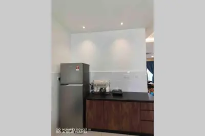 a kitchen with a stainless steel refrigerator and wooden cabinets at PANGKOR 66’s HOME in Kampong Sungai Udang