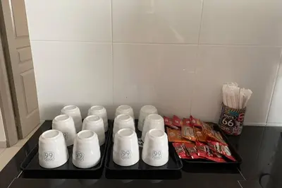 a refrigerator with white cups and snacks on a shelf at PANGKOR 66’s HOME in Kampong Sungai Udang