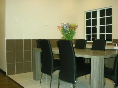 a dining room table with chairs and a vase of flowers at CH Green Stay Resort Apartment in Cameron Highlands