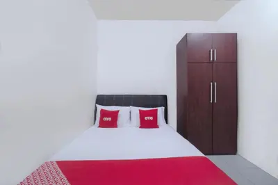 a bedroom with a bed with red pillows and a cabinet at Guesthouse Fasa 2B in Seri Manjung
