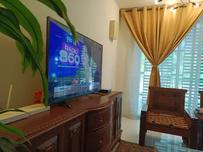 a living room with a large flat screen tv on a cabinet at Kayu Cengal Homestay in Seri Iskandar
