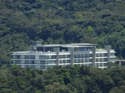 a large white building in the middle of trees at Bugdet Apartment in Brinchang