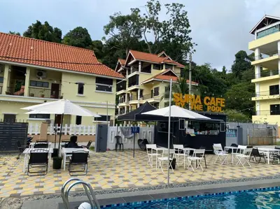 a pool with chairs and umbrellas next to a building at SURIA BEACH RESORT Pangkor in Pangkor