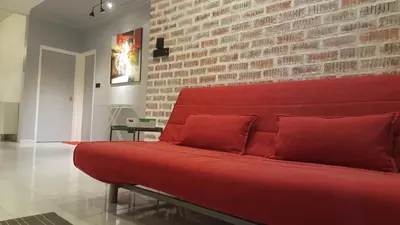 a red couch in a room with a brick wall at Tulip Hotel in Ipoh
