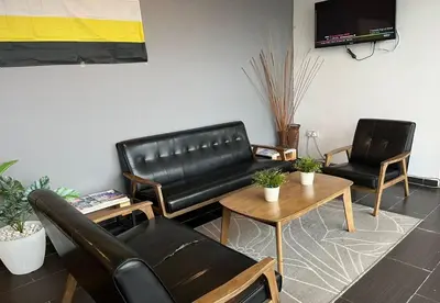 a living room with a black leather couch and two chairs at 1108 Hotel Sungkai in Sungkai