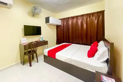 a bedroom with a bed and a desk with a television at OYO 90369 Safari Hotel Lumut in Kampong Pundut