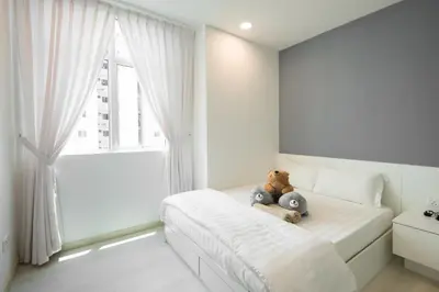 a teddy bear sitting on a bed in a bedroom at Straits Garden Suites by The Homestay Helper in George Town