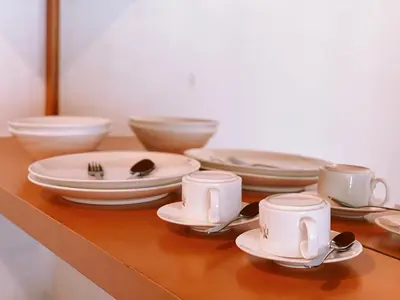 a table with plates and cups and utensils on it at Nova Apartments near Kea Farm in Brinchang