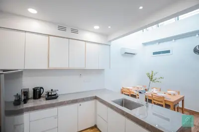 a kitchen with white cabinets and a sink and a table at Jomstay MUJI 19 & 7 INN Ipoh Garden 8-10 pax in Ipoh