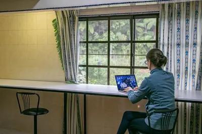 a woman sitting in a chair with a laptop in front of a window at 100 Oastel coLiving in Tanah Rata