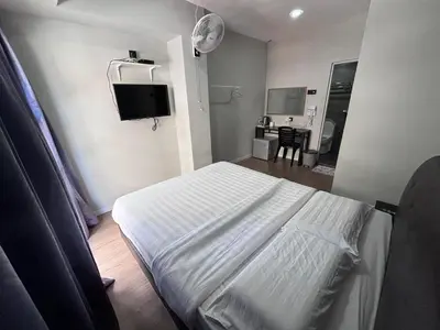 a bedroom with a white bed and a tv at OU INN Cameron Highlands ,Ferm Nyonya Restaurant in Tanah Rata