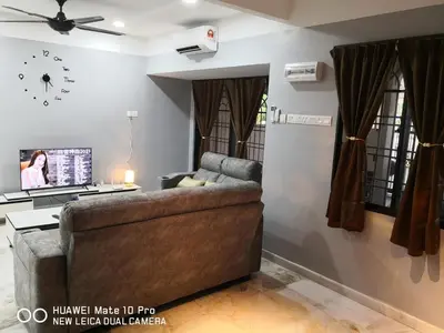 a living room with a couch and a clock on the wall at TB HOMESTAY Tasek klebang(taman bertuah) 10pax wifi in Chemor