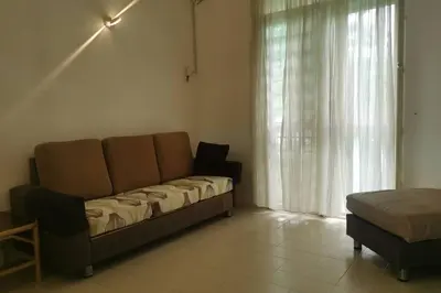 a couch sitting in a living room with a window at Cozy NEAR-BEACH Apartment - LazyCats' Den in Batu Ferringhi