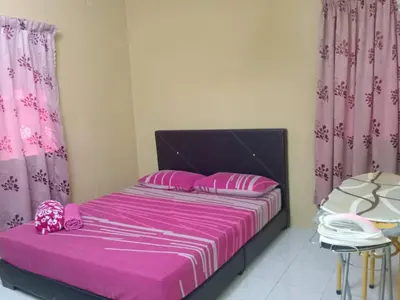 a bedroom with a bed with pink sheets and pink curtains at Irfans HomestayDouble storey in Seri Manjung