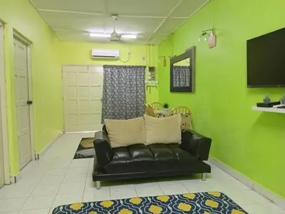 a living room with a black leather couch and green walls at Irfans HomestayDouble storey in Seri Manjung