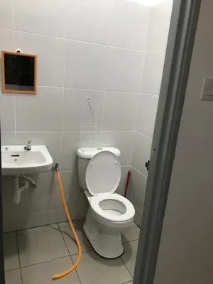 a bathroom with a toilet and a sink with a hose at An-Nur Homestay in Sungai Petani