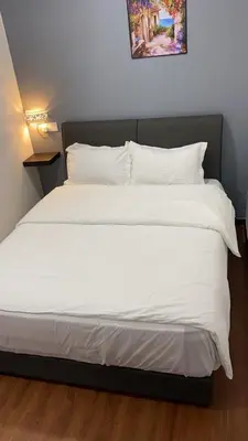 a bed with white sheets and pillows in a room at Hi TechSTAY in Lunas