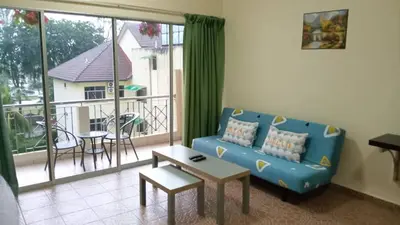 a living room with a blue couch and a balcony at Apartment Teluk Batik in Lumut