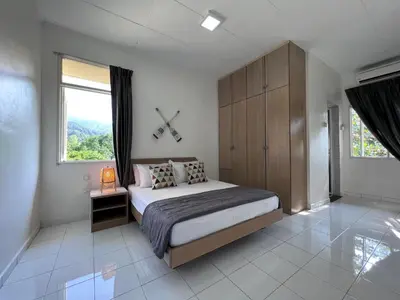 a bedroom with a bed and a clock on the wall at EE's Beach House - Homestay 3 min walk to beach in Batu Ferringhi