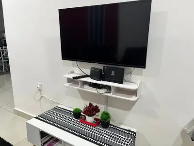 a flat screen tv on a white wall with potted plants at Embon Homestay in Padang Serai