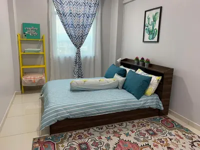 a bedroom with a bed with blue sheets and a rug at Ammar SkyHome Ipoh in Ipoh