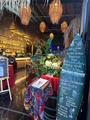 a restaurant with a surfboard in front of a counter at Beach Resort Home Stay SRI SAYANG APARTMENT BATU FERRINGHI 2BEDROOM in Batu Ferringhi