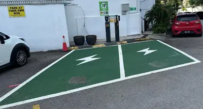 a parking lot with a green and white arrow painted on the street at Beach Resort Home Stay SRI SAYANG APARTMENT BATU FERRINGHI 2BEDROOM in Batu Ferringhi