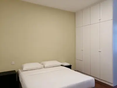 a white bedroom with a bed and white cabinets at Bayu Emas Apartment by Wellington Resorts in Batu Ferringhi
