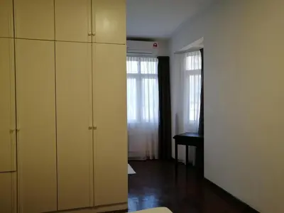 a room with white cabinets and a table and two windows at Bayu Emas Apartment by Wellington Resorts in Batu Ferringhi