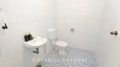 a white bathroom with a toilet and a sink at CofyHill Retreat in Kampong Changkat Tualang