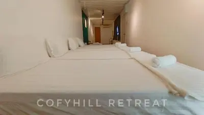 a row of white beds in a room at CofyHill Retreat in Kampong Changkat Tualang