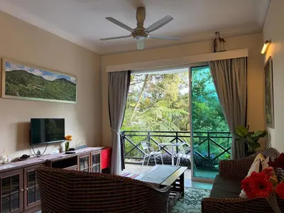 a living room with a view of a balcony at Gerard's Place Nature Heaven Apartment in Tanah Rata