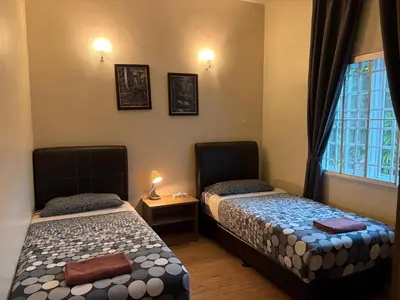 two beds in a room with a window at Gerard's Place Nature Haven Apartment in Tanah Rata