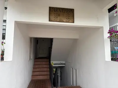 a clock on the wall of a building with a stairway at Gerard's Place Nature Haven Apartment in Tanah Rata