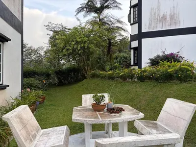 a table and two chairs on a patio with a yard at Gerard's Place Nature Haven Apartment in Tanah Rata