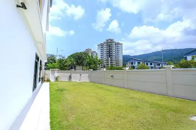 a backyard with a white fence and grass at FERRINGHI RESORT 5-BEDROOM with POOL, BBQ SET, WiFi, Netflix & WALK to BEACH in Batu Ferringhi