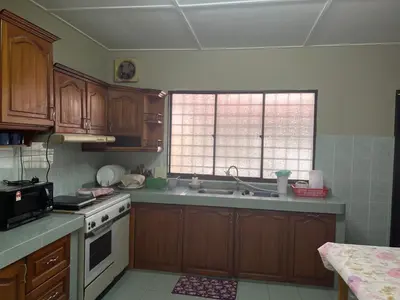 a kitchen with wooden cabinets and a white stove top oven at To' Teh Homestay in Ipoh