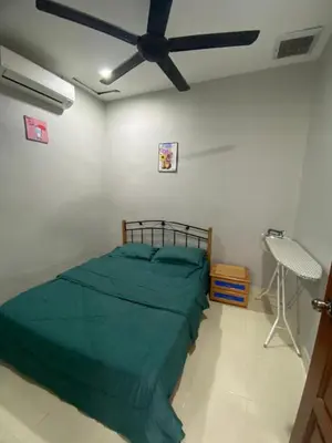 a bedroom with a green bed and a ceiling fan at MAMA homestay in Bagan Serai