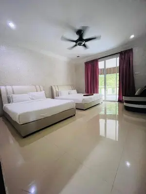 two beds in a bedroom with a ceiling fan at Homestay Seri Pangkor in Pangkor