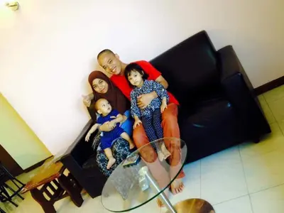 a family sitting on a couch with a glass table at AGODA C VIEW @ Sri Sayang Beach Resort in Batu Ferringhi