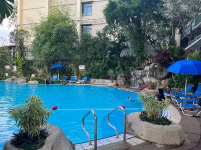 a large blue pool with chairs and an umbrella at Paradise by the Sea in Penang by Veron at Rainbow Paradise in Tanjung Bungah