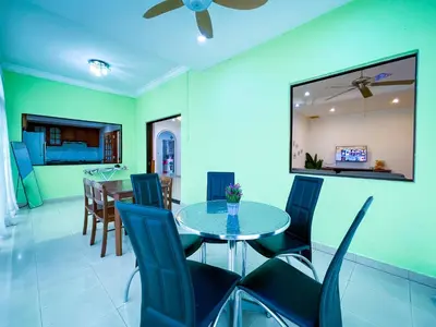 a dining room and living room with a table and chairs at Tupai Mas Semi-D 4BR 2mins to LakeGarden & Zoo in Taiping