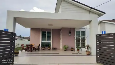 a white house with a patio with a table and chairs at Mysa Homestay in Kampong Batu Dua