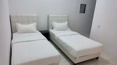 two beds in a room with white sheets and pillows at Malim Nawar holiday house in Malim Nawar