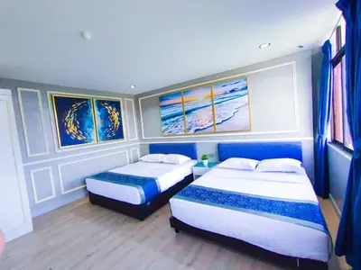 a bedroom with two beds and paintings on the wall at 61 Hotel in Gua Musang