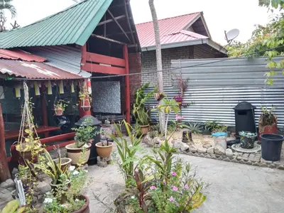 a garden in front of a house with potted plants at Nazri Nipah Camp Pangkor in Kampung Teluk Nipah